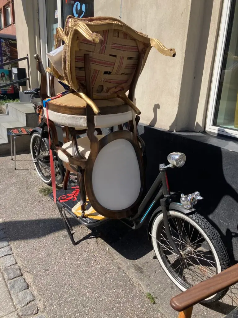 Well packed Long John bicycle with FRB Studio logo and white wall tires in front of upholstery store in Frederiksberg